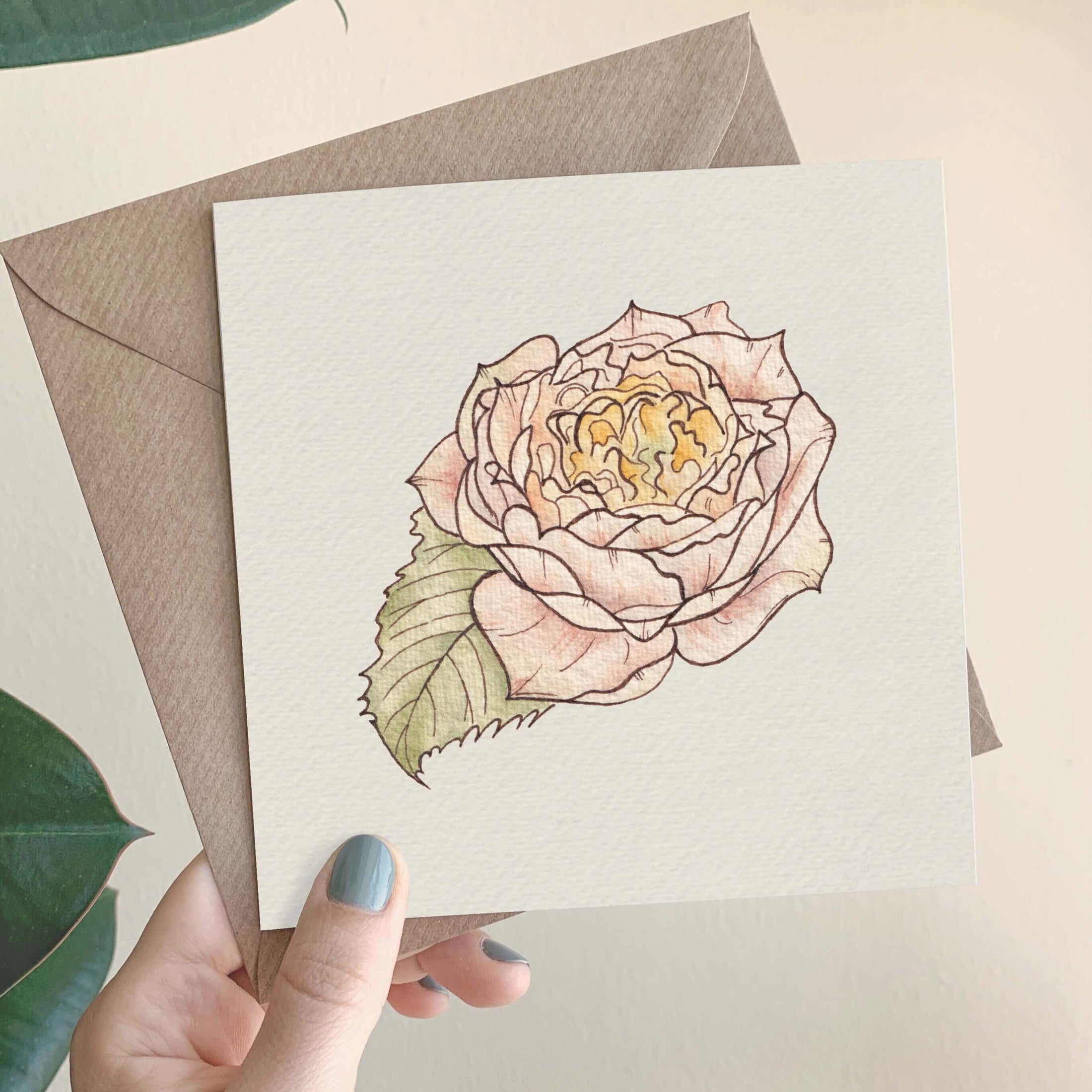 Querin Creations square greeting card with a pink rose illustration held by a hand with green nail polish.