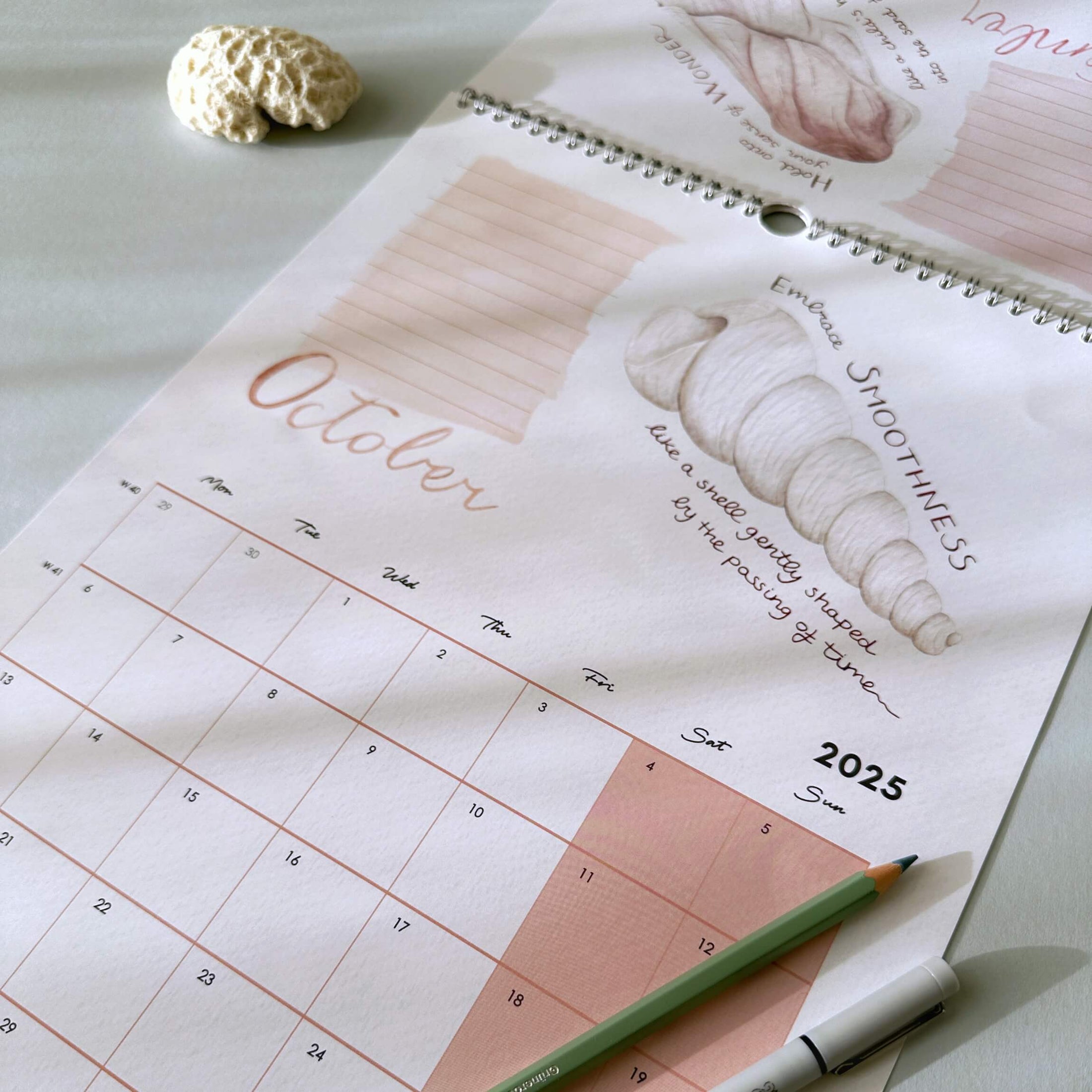 Calendar for October 2025 with a pencil and decorative object on a light surface