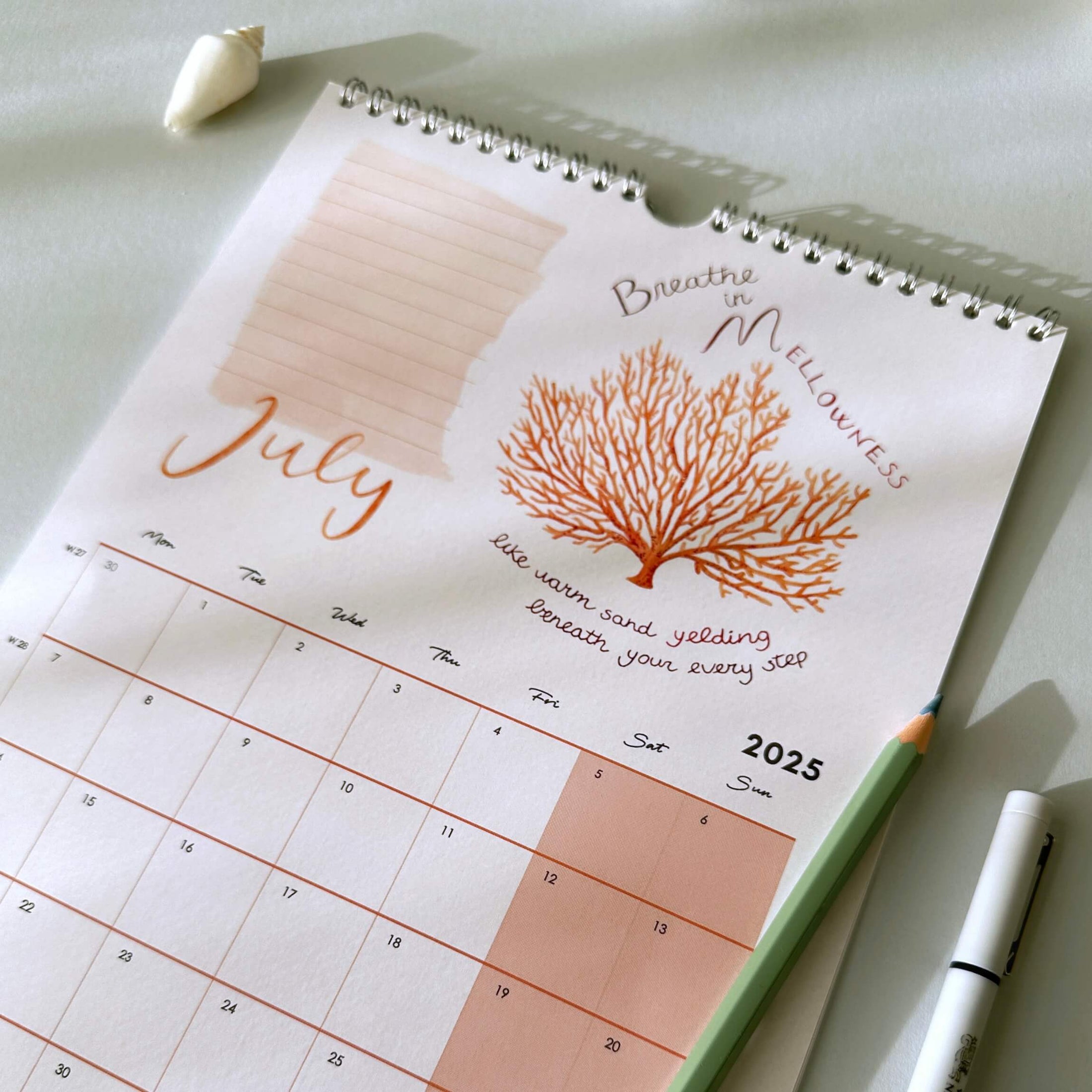 Calendar with a coral illustration and inspirational quote on a light surface.