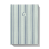 Notebook with blue striped pattern cover and floral monogram on a white background