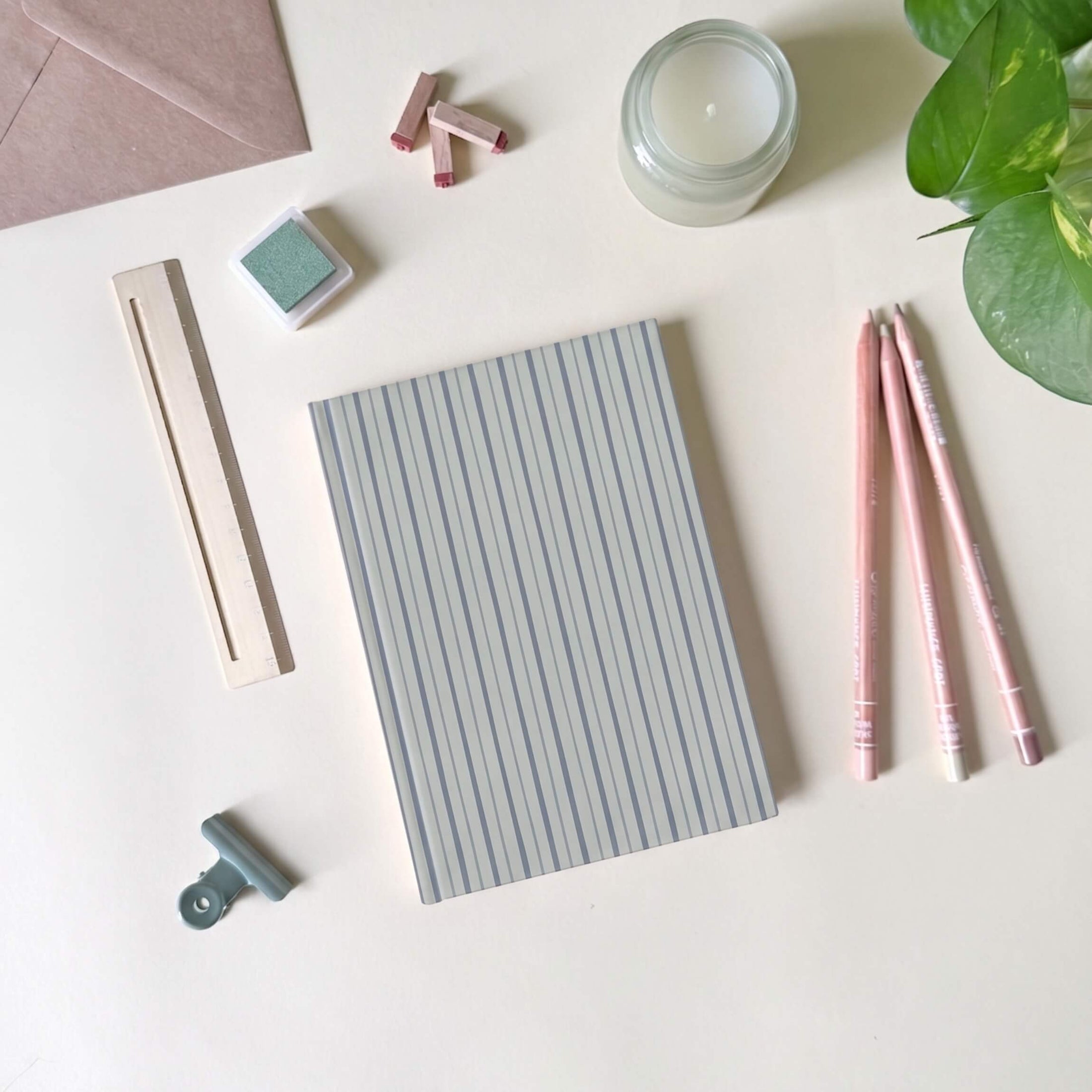 Blue stripes notebook with stationery items on a light desk