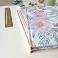 Load image into Gallery viewer, Close up of the hardcover spine of a floral and stripes notebook on a white surface with stationery items

