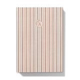Notebook with red striped cover and floral monogram on a dust pick background