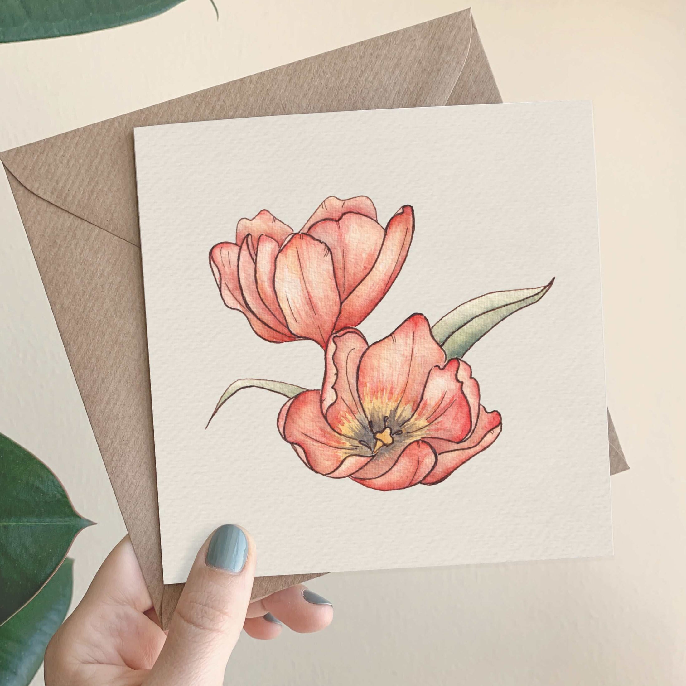 Querin Creations square greeting card with two pink poppy flowers held by a hand against a beige background and craft envelope 