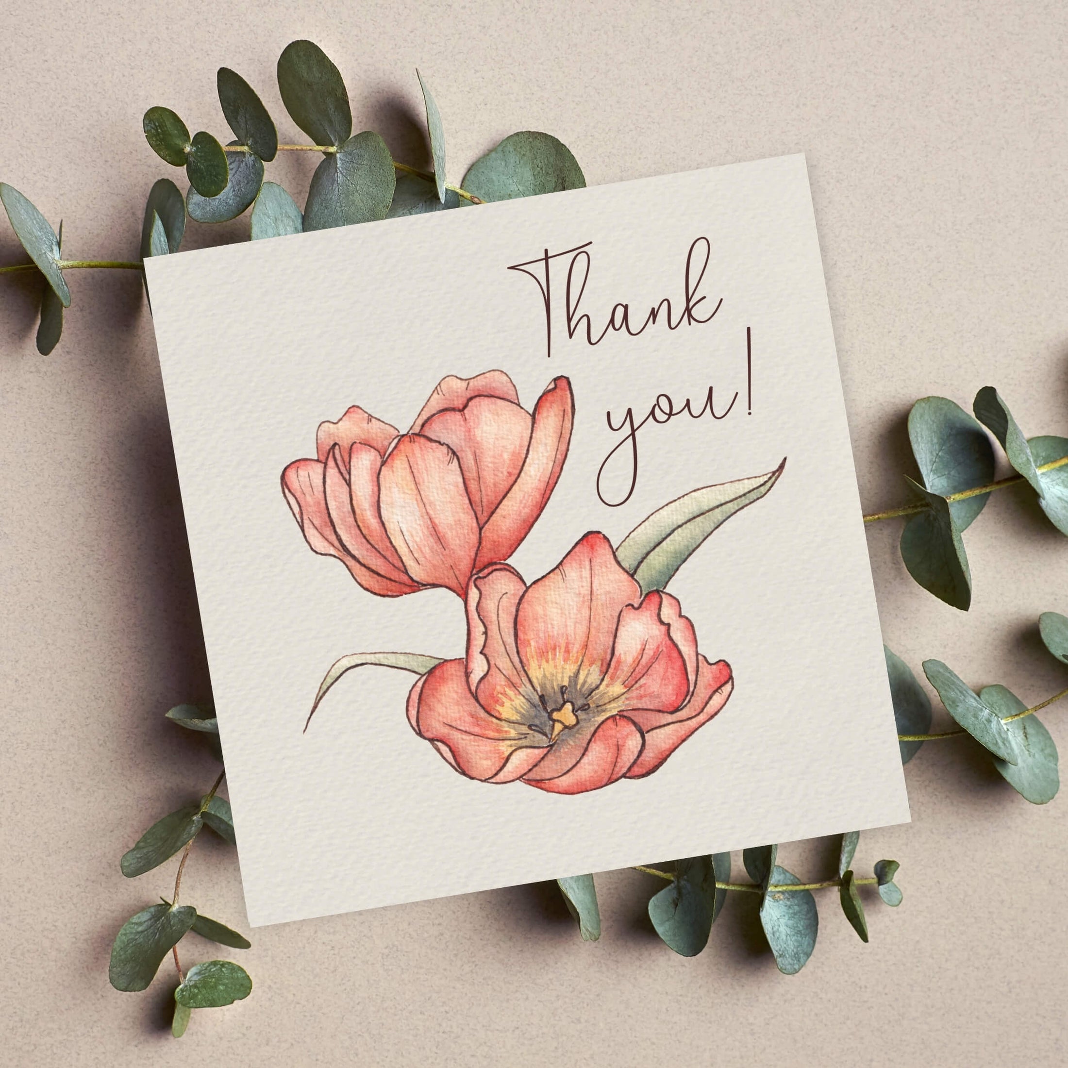 Greeting card with pink flowers and 'Thank you!' text, surrounded by eucalyptus leaves on a beige background
